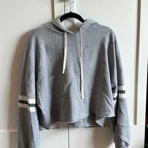 Grey cropped sweatshirt with green/white stripes on the sleeves.